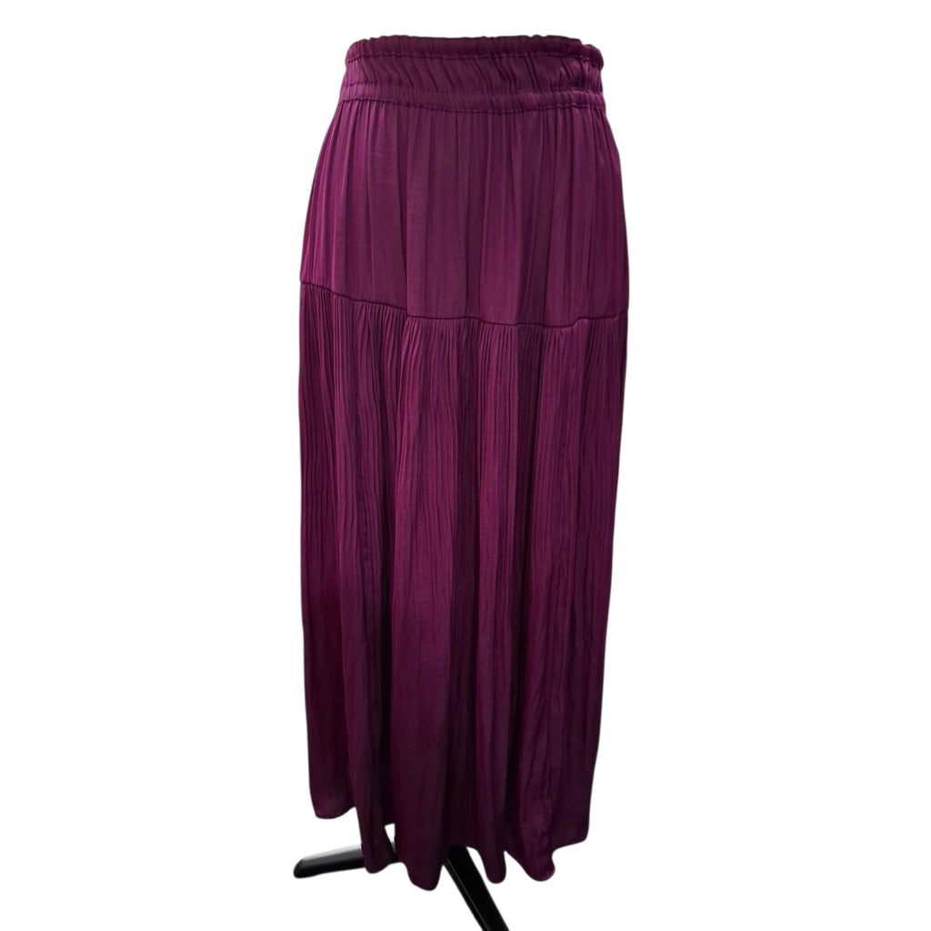 A pleated, tiered maxi skirt in a deep plum purple color, displayed on a black stand against a plain white background.