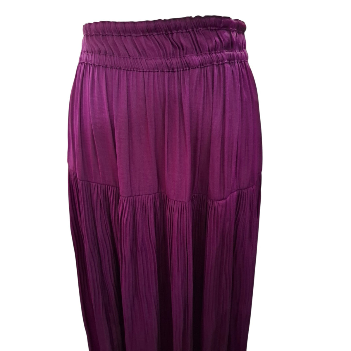 A close-up of a pleated skirt in a rich magenta-purple color, featuring an elastic waistband and tiered construction, shown against a plain white background.