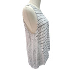 A sleeveless white knit top with a black grid pattern on one side and a sheer white lace overlay on the other, displayed on a mannequin torso against a white background.