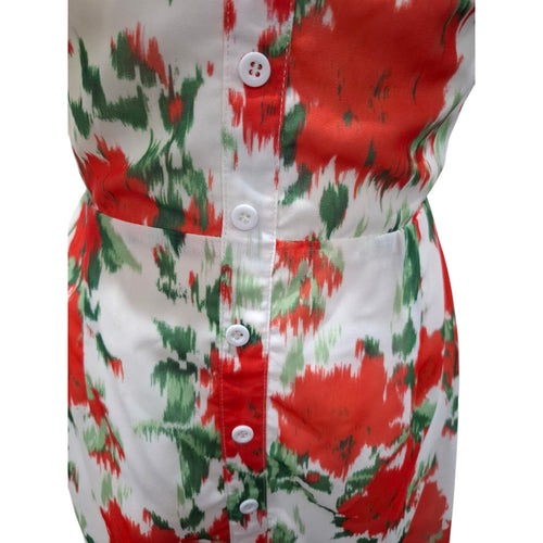 A close-up of a sleeveless button-front top or dress with a bold red, green, and white abstract ikat-style print, shown against a plain white background.