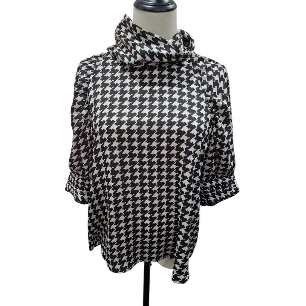 A black and white houndstooth patterned blouse with a high draped mock neck and elbow-length sleeves, displayed on a mannequin torso against a white background.
