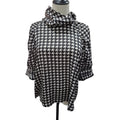A black and white houndstooth patterned blouse with a high draped mock neck and elbow-length sleeves, displayed on a mannequin torso against a white background.