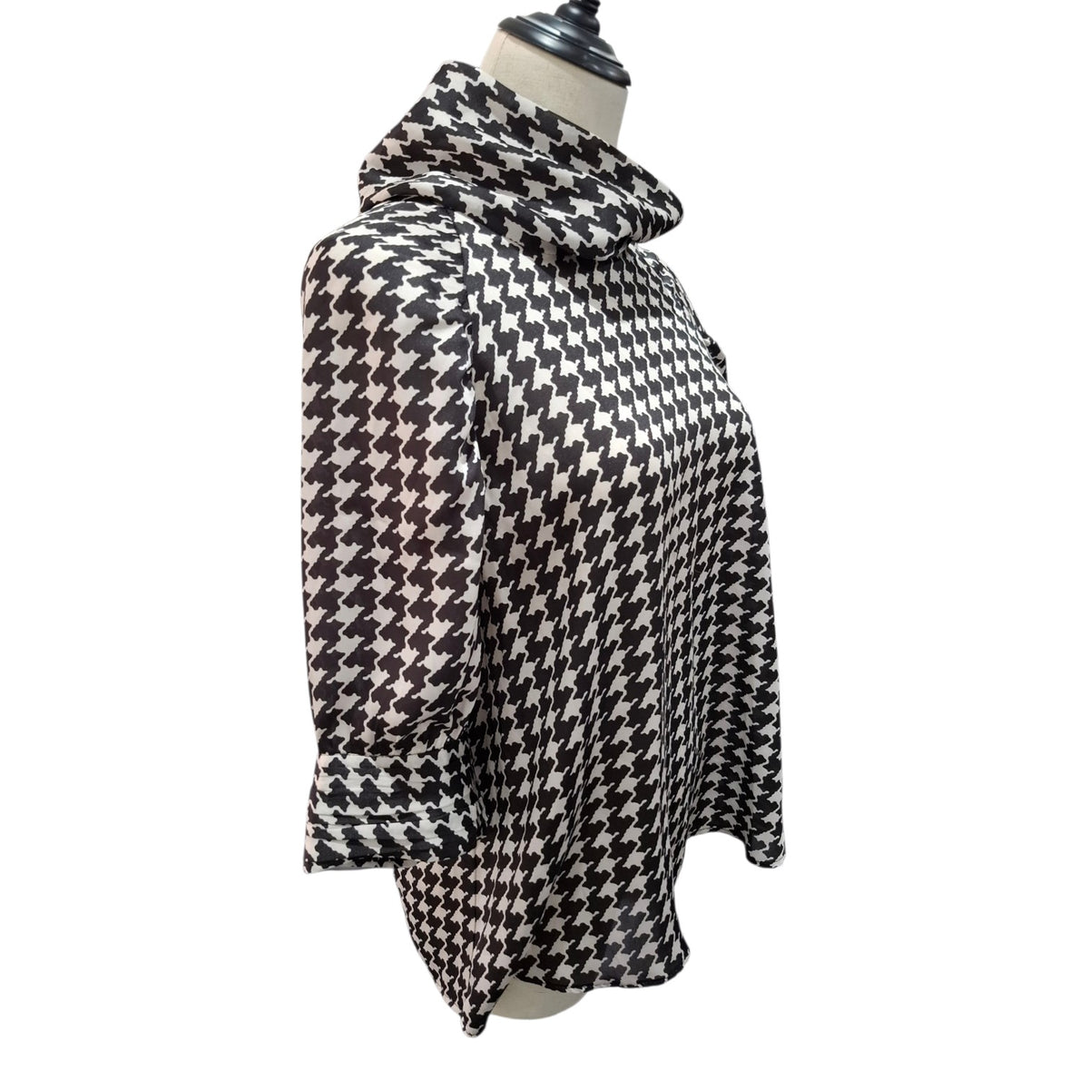 A black and white houndstooth patterned long-sleeve top displayed on a mannequin torso against a plain white background.