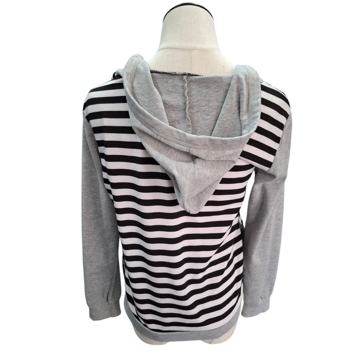 A women's long-sleeve hoodie top displayed on a mannequin torso, featuring a black and white wavy stripe pattern across the body and sleeves, with solid heather gray sleeves and hood.