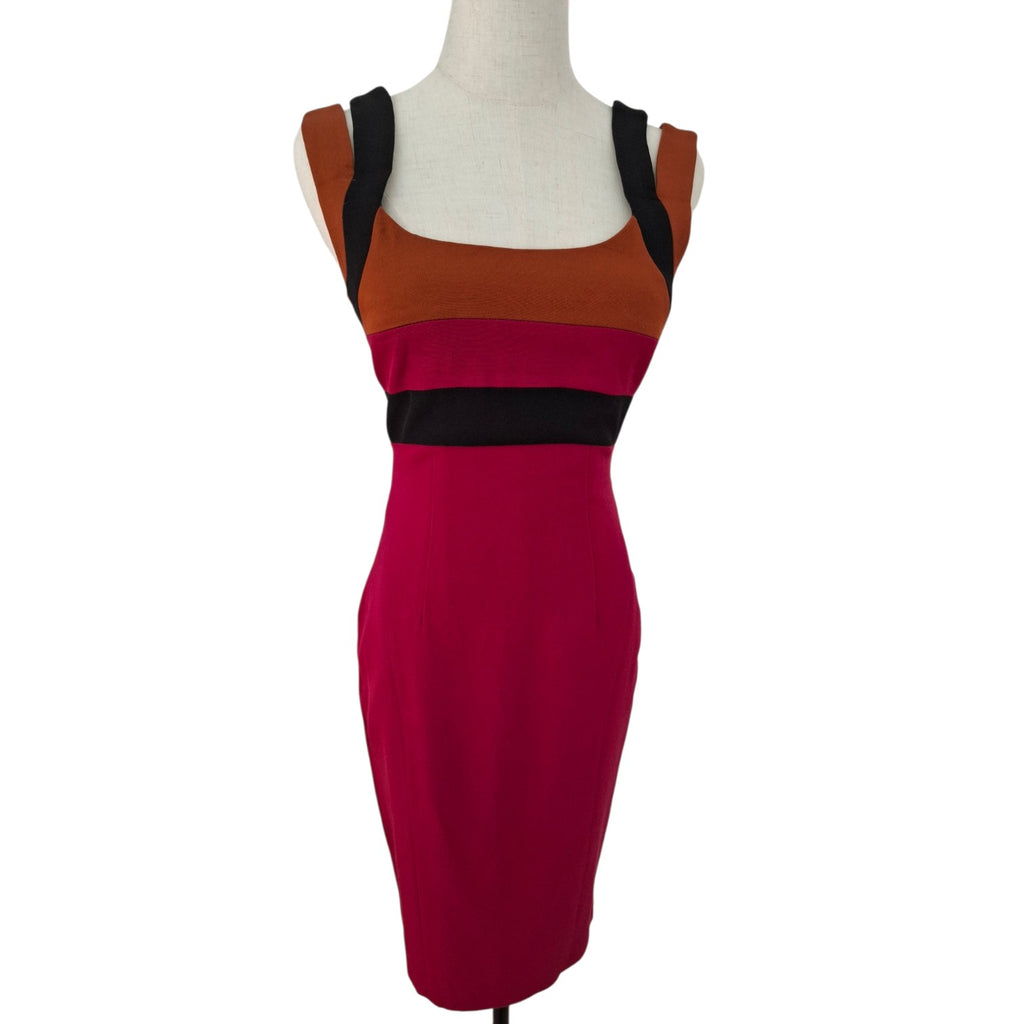 A sleeveless bodycon dress displayed on a white mannequin torso against a plain white background. The dress features a color-blocked design with a rust-orange upper section, a black band across the chest, and a deep magenta lower section.