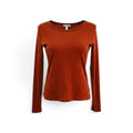 A rust-orange long-sleeve crewneck knit top displayed on a white mannequin torso against a white background.