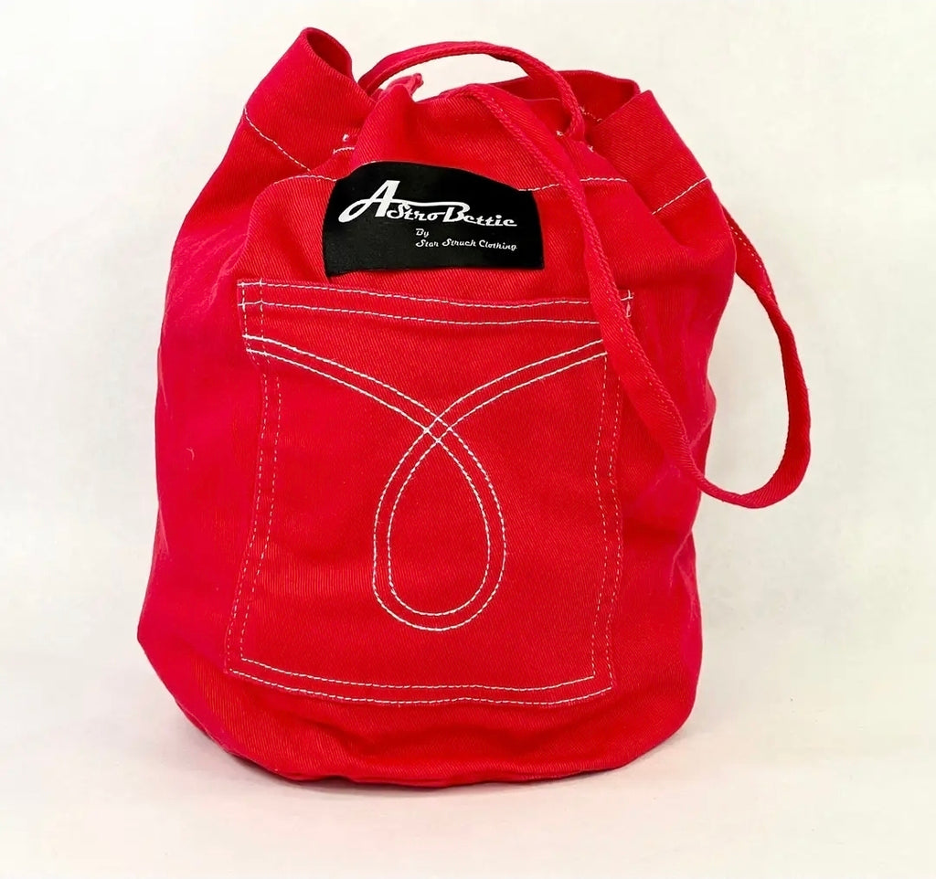A bright red canvas bucket bag with white contrast stitching, featuring a front pocket designed to look like a denim pocket and a black brand label that reads 'Aberdeen'.