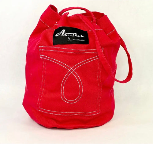 A bright red canvas bucket bag with white contrast stitching, featuring a front pocket designed to look like a denim pocket and a black brand label that reads 'Aberdeen'.